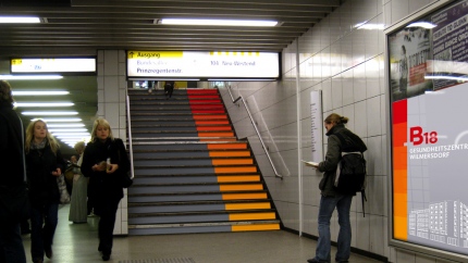 Fotomontage des von okamo aus Berlin gestalteten Designs für eine U-Bahnhof-Treppen-Werbung und ein Werbeplakat für „B18 Gesundheitszentrum Wilmersdorf“ mit dem charakteristischen Farbverlauf